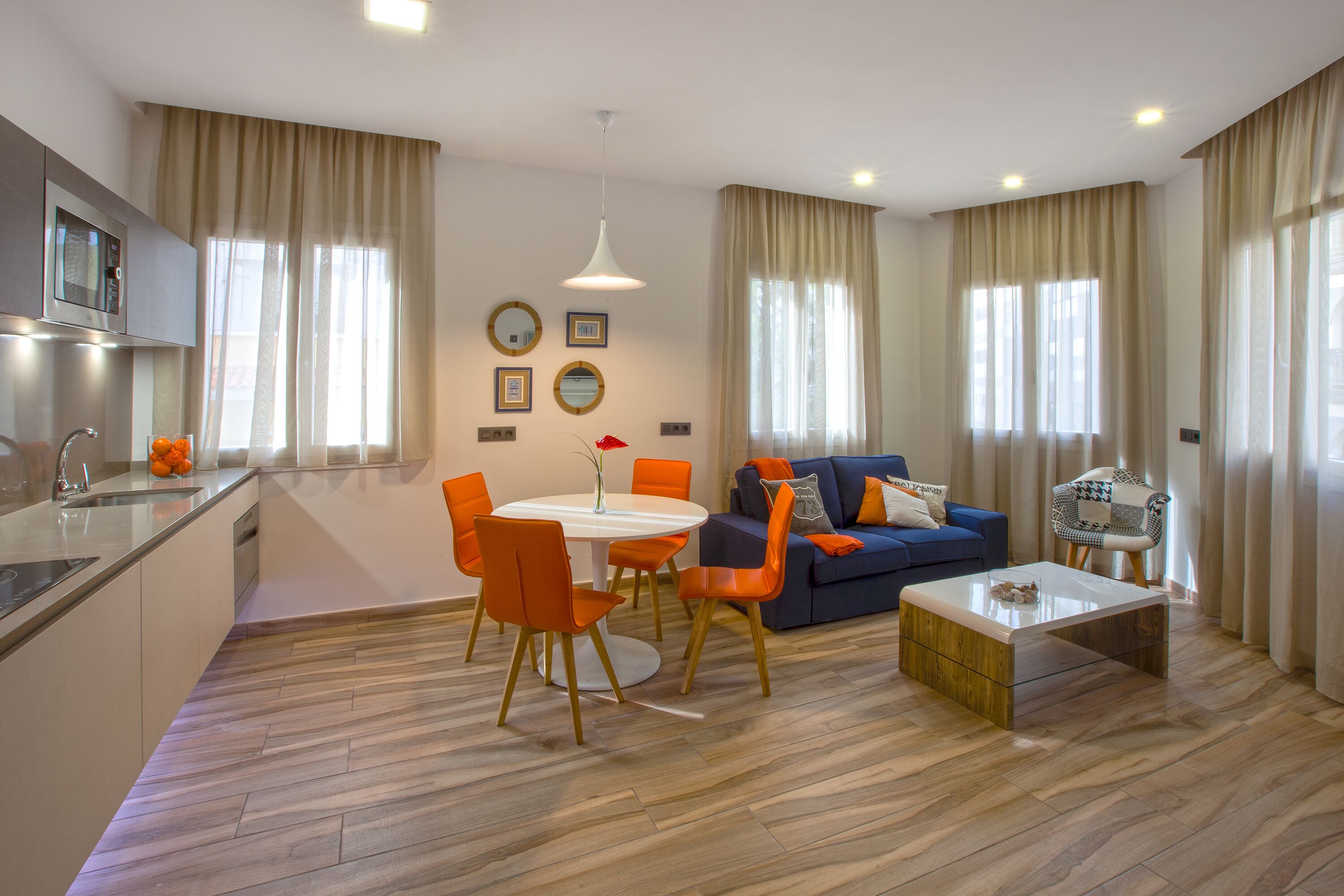 A modern living room with a dining area, a sofa, a coffee table, and a kitchen with a microwave.