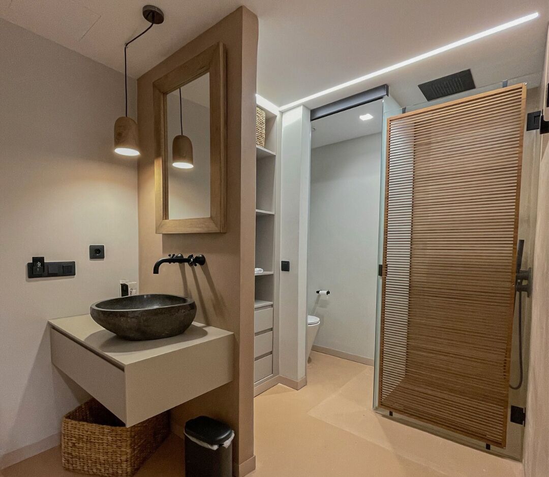 Une salle de bain moderne avec un grand miroir, un lavabo sur colonne et une porte en bois.