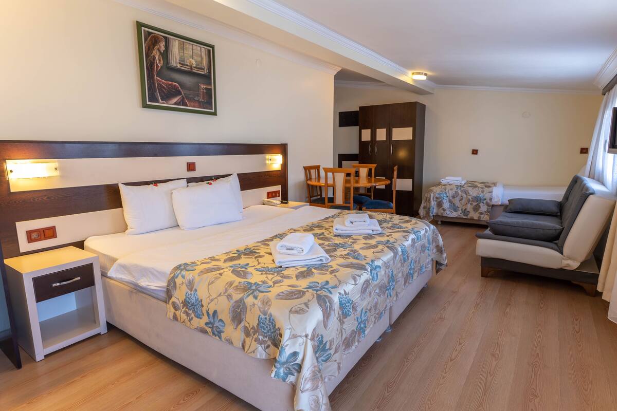 A hotel room with a large bed, a small table, a sofa, and a desk.