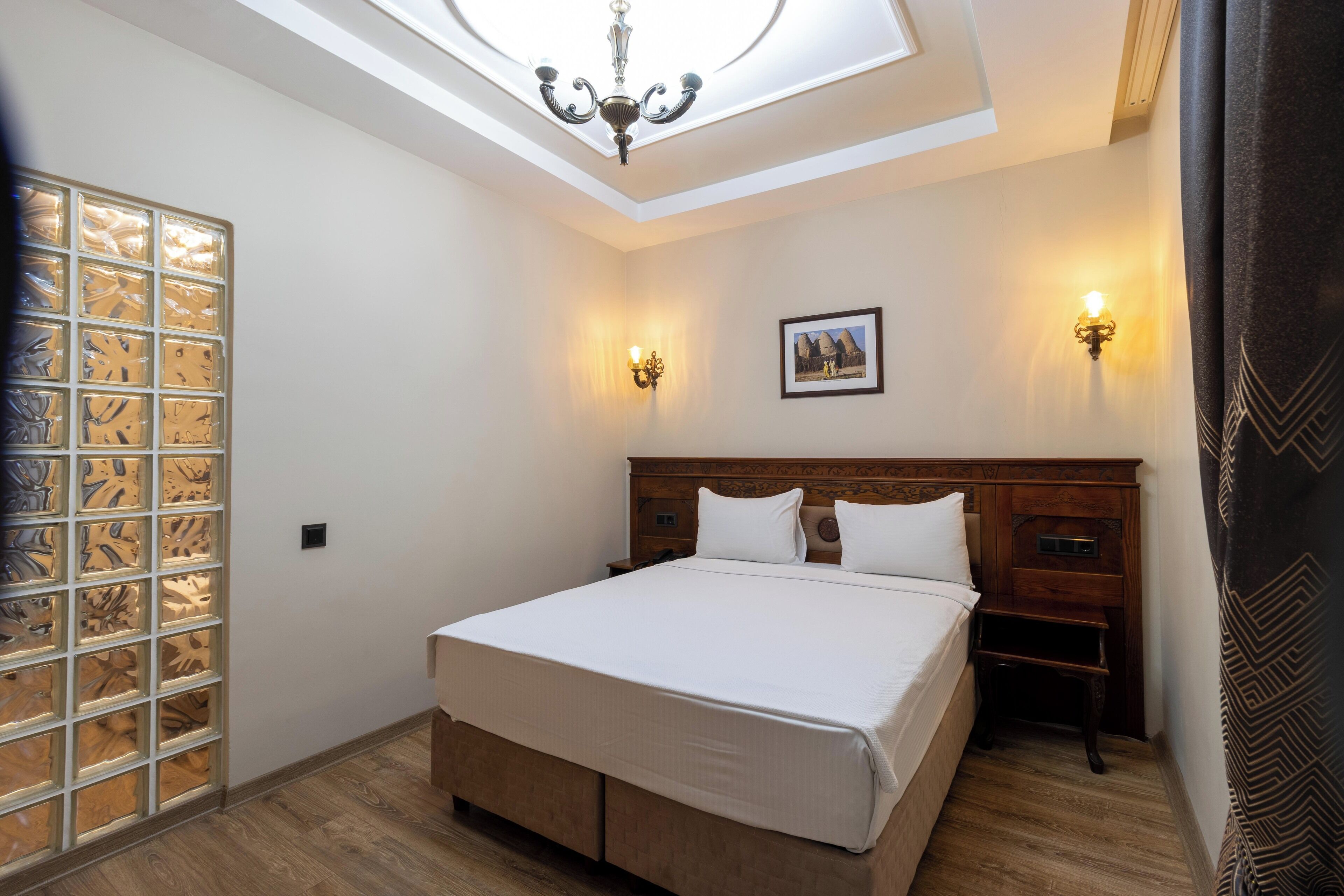 A bedroom with a skylight, a bed, two bedside tables, and a wall-mounted picture.
