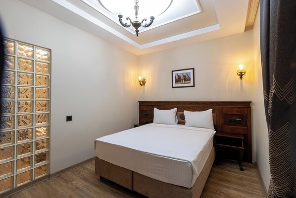 A bedroom with a skylight, a bed, two bedside tables, and a wall-mounted picture. - Hotel El-Ruha (Sanliurfa)