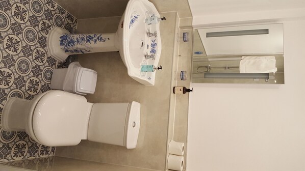 Un baño con inodoro, lavabo y espejo.