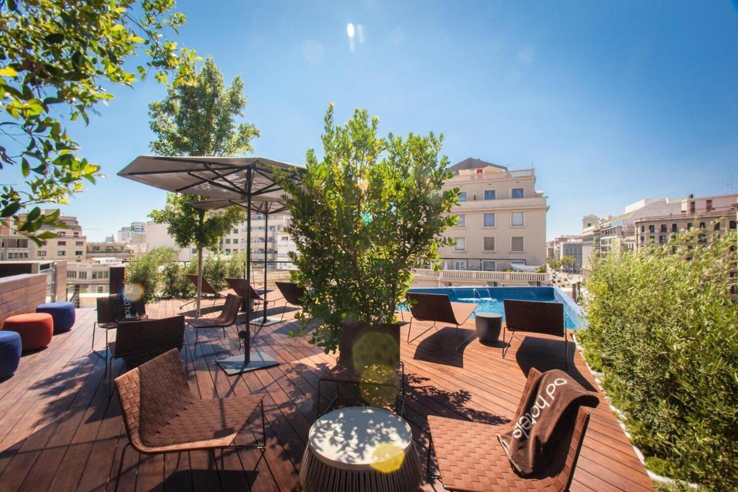 Terraço no telhado com piscina, área de estar ao ar livre e vista para edifícios próximos.