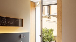 A modern hotel room with a large bed, a bedside table, a nightstand, and a view of a balcony with greenery. - Eurostars Barcelona Central (Barcelona)