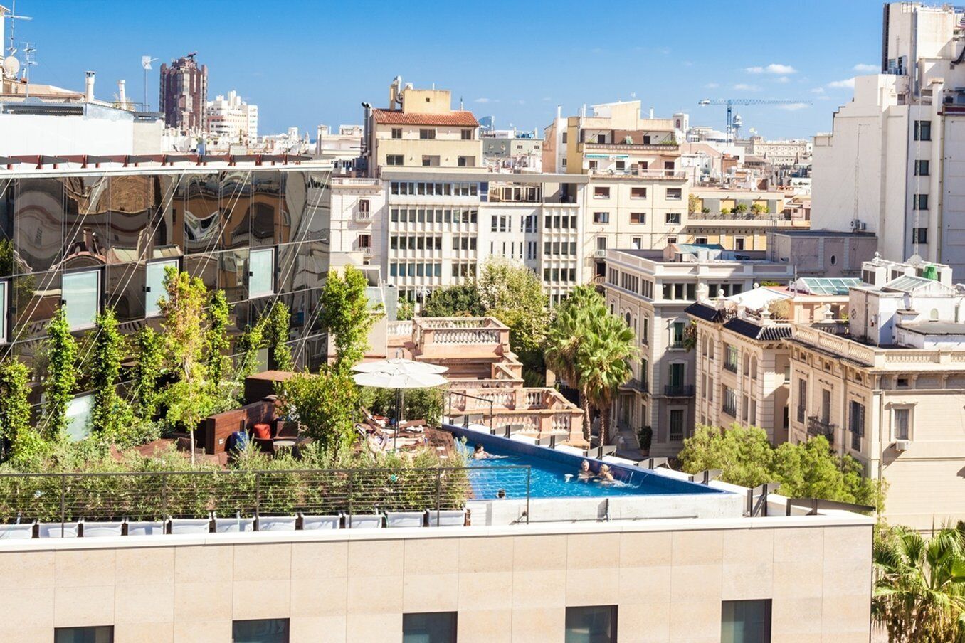 A rooftop pool with a view of the cityscape, surrounded by trees and buildings.
