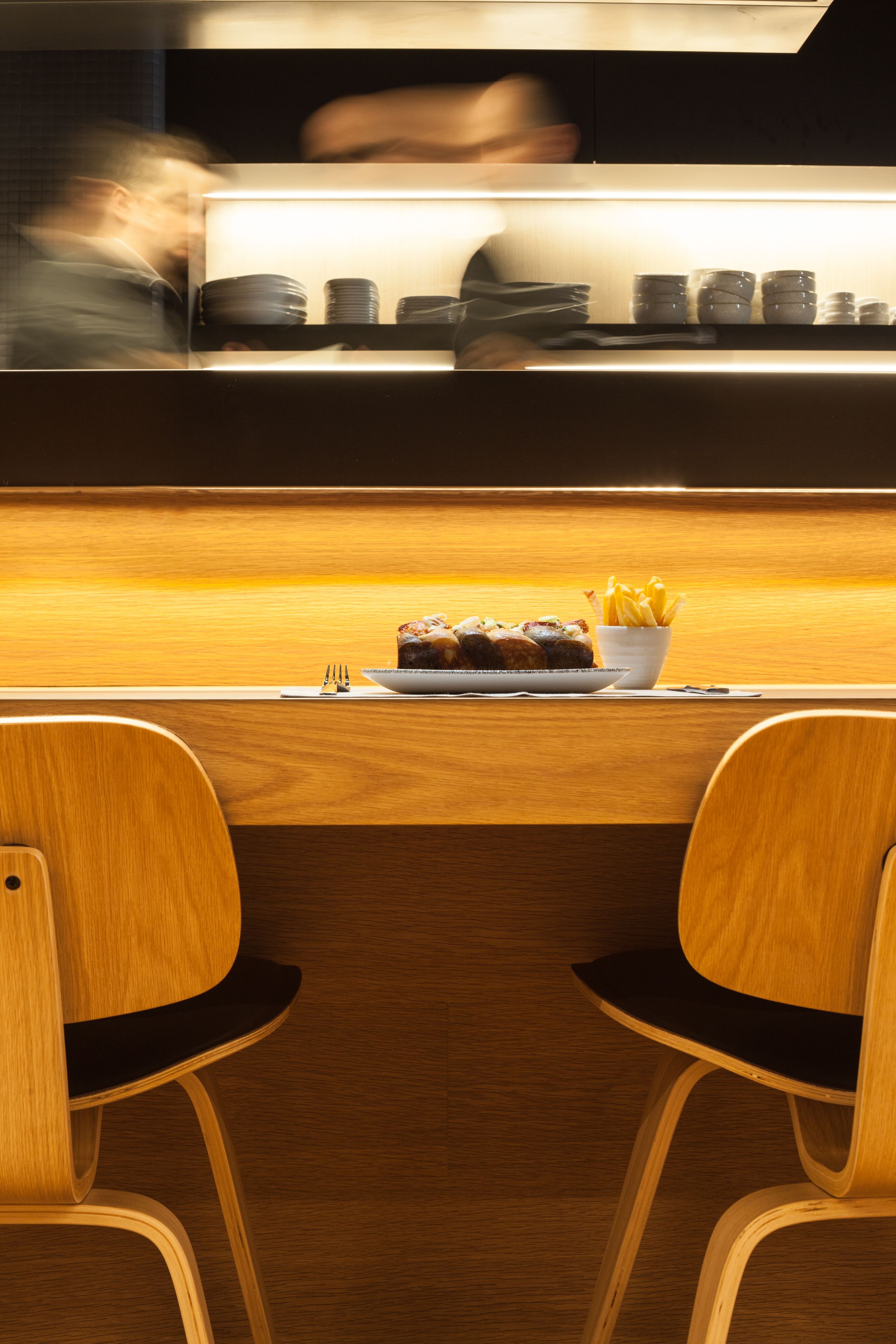 Un restaurante con una barra de madera y dos sillas.