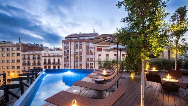 A rooftop pool area with lounge chairs and tables, surrounded by buildings. - Eurostars Barcelona Central (Barcelona)