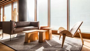 A modern living room with a leather sofa, wooden coffee tables, and a lounge chair. - Eurostars Barcelona Central (Barcelona)