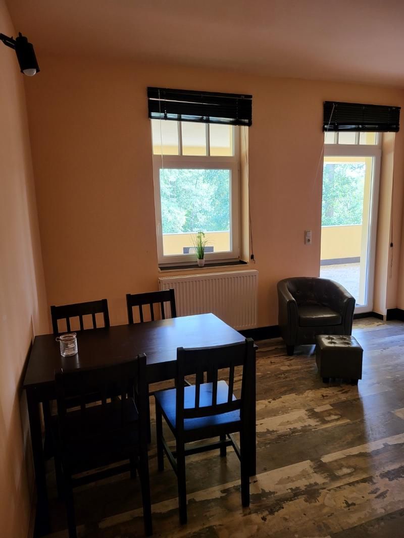 Un comedor con una mesa, sillas, un radiador y una ventana con persianas.
