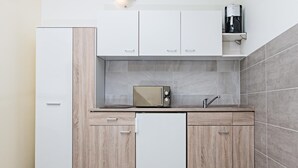 A modern kitchen with a built-in microwave, a coffee maker on a shelf, and a refrigerator. - Landhaus Bettina (Fulda)