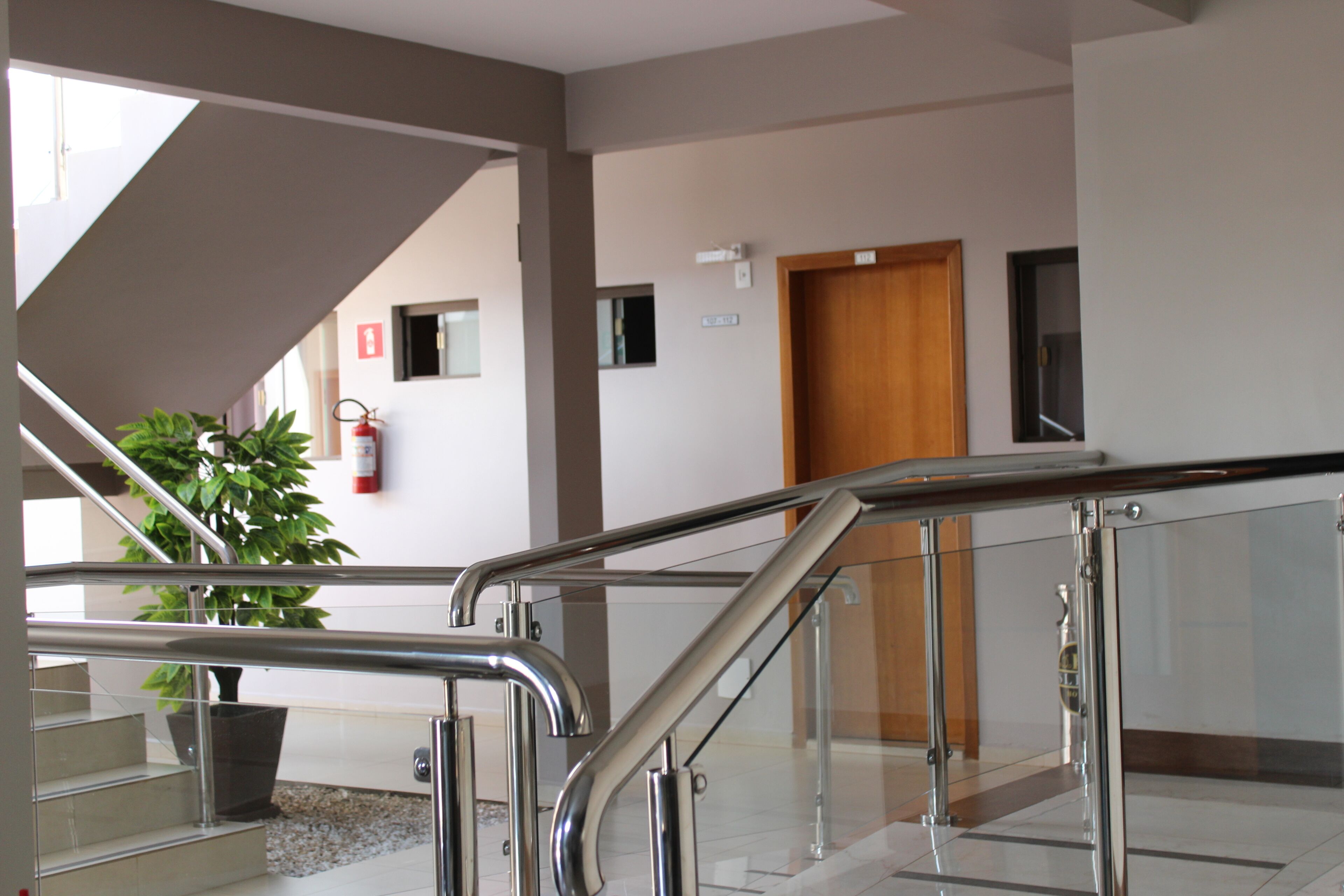 A modern indoor staircase with glass railings and a potted plant.