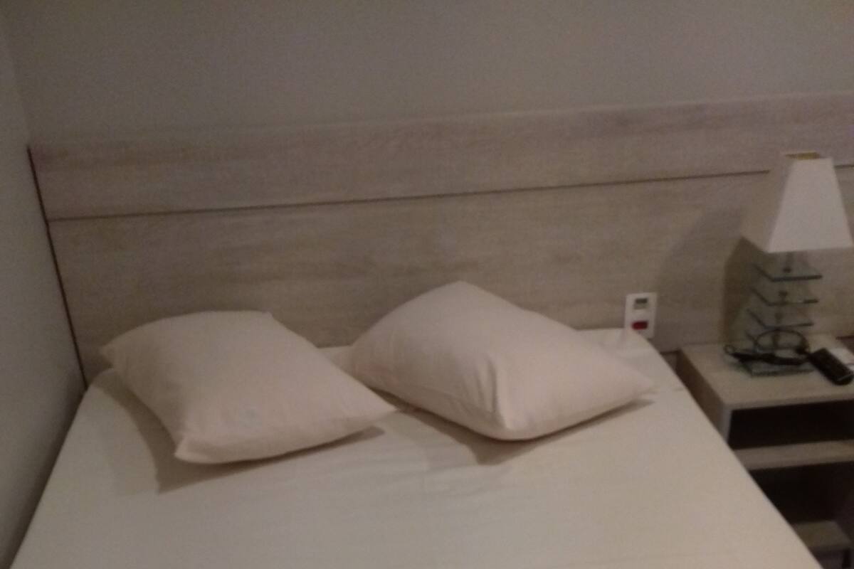 Una cama bien hecha con dos almohadas y dos toallas dobladas.
