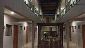 Een moderne hotelgang met een centraal gelegen eetgedeelte, meerdere deuren en een plafondventilator.
