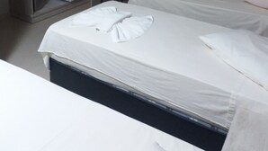 Een hotelkamer met twee bedden, een kledingkast, een televisie en een raam met gordijnen.