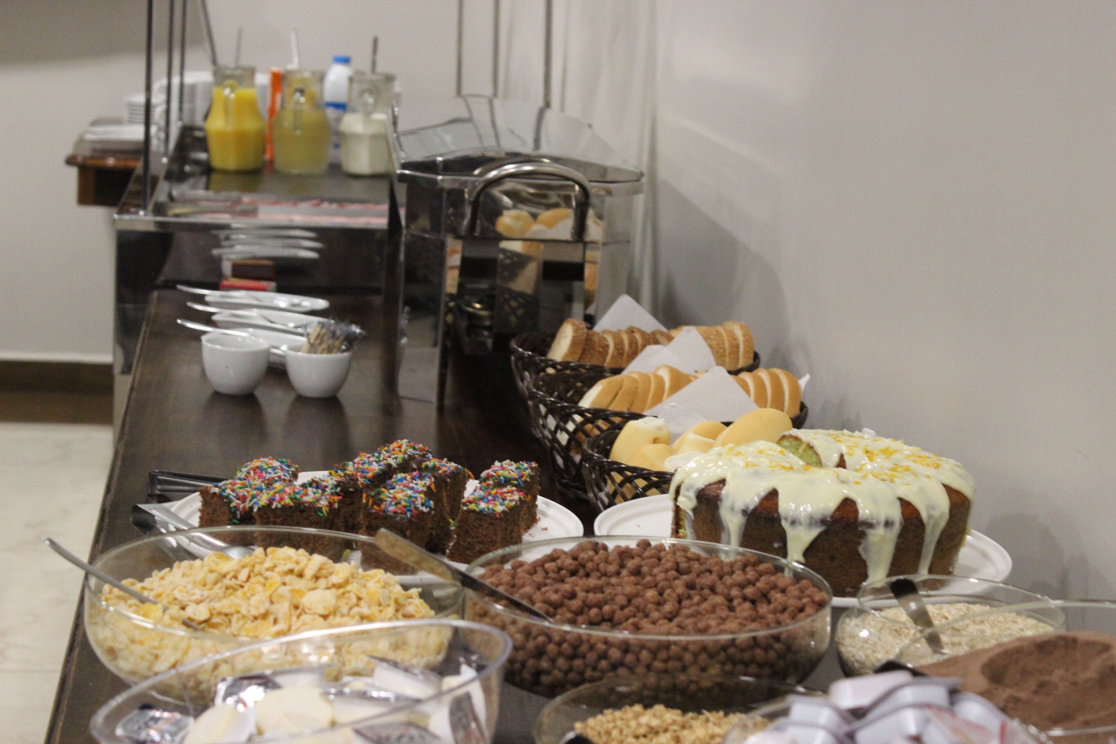 A buffet table with various food items including cakes, pastries, and cereals.