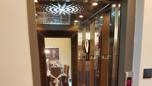 An elevator with a reflective interior, a digital display, and a control panel. - Villa Carlos (Patras)