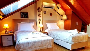 A bedroom with two beds, wooden flooring, and a sloped ceiling. - Villa Carlos (Patras)