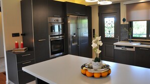 Una cocina moderna con armarios oscuros, electrodomésticos de acero inoxidable y una isla central con fruteros y velas.