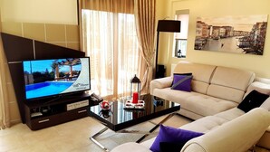 Una sala de estar moderna con televisor, sofá y un cuadro de un paisaje urbano.