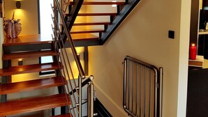 Una escalera moderna con peldaños de madera y barandillas de metal, que conduce a un piso superior.