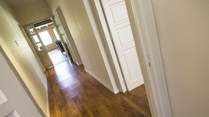 Un couloir avec un plancher en bois et des portes blanches.