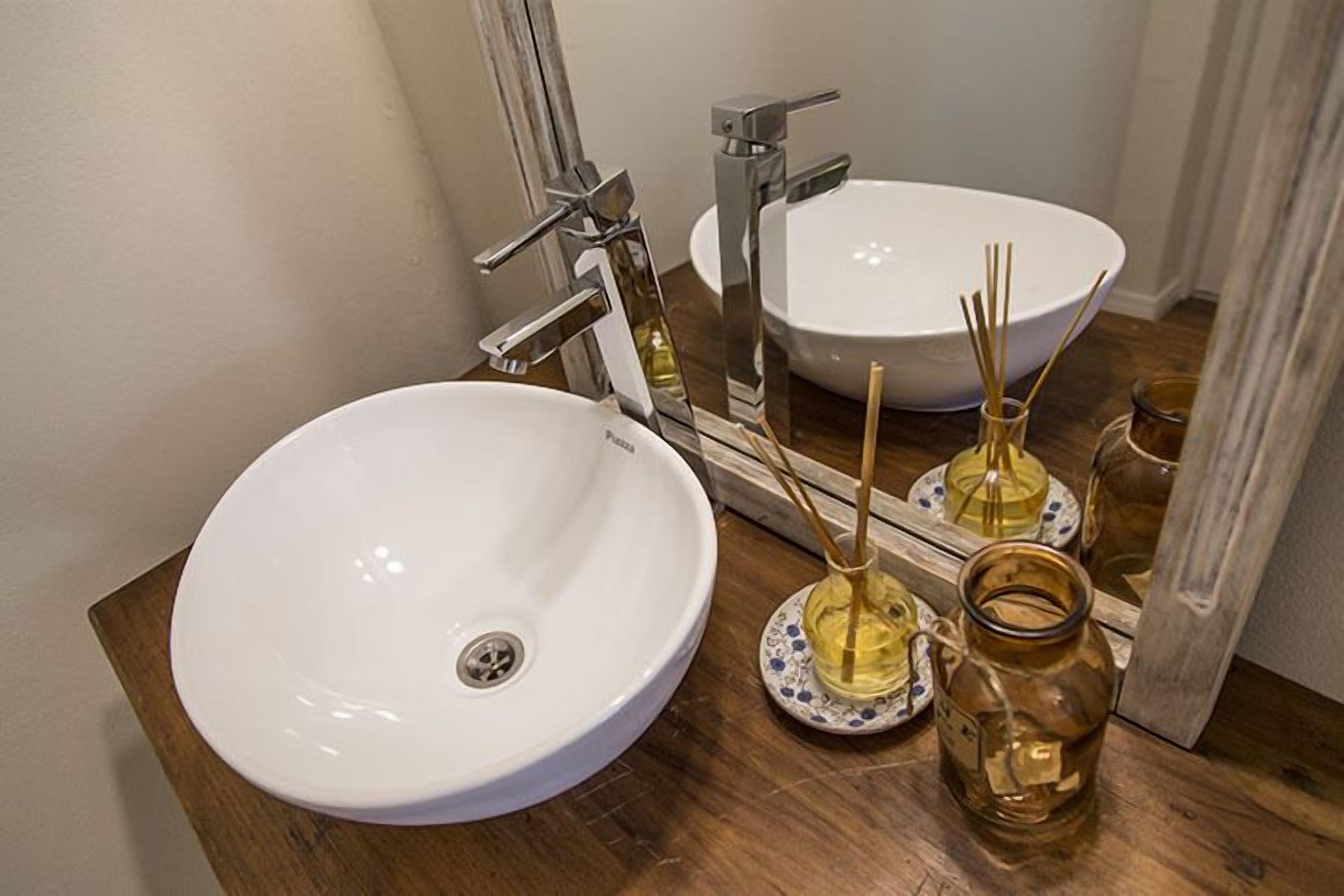 Une salle de bain avec un lavabo blanc, un miroir et un meuble-lavabo en bois.