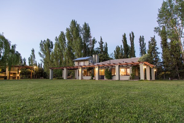 A modern house with a covered patio, surrounded by a well-maintained lawn and tall trees.