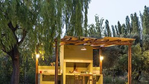Une structure extérieure en bois, dotée d’une table et de chaises, entourée d’arbres.