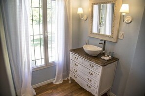 A bathroom with a white vanity, a large mirror, and two wall-mounted lights.