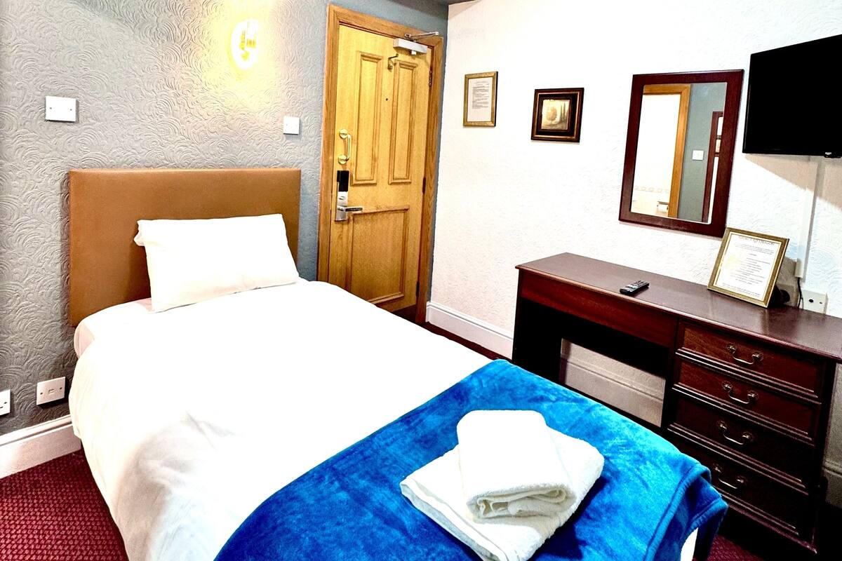 Quarto de hotel com cama, cômoda, espelho e porta.