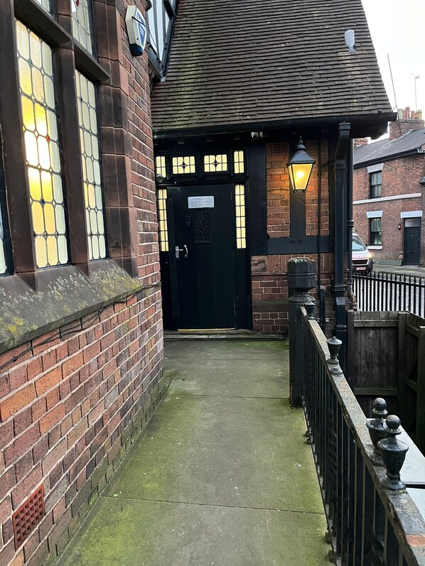 A narrow alleyway leading to a black door with a sign indicating hotel reception.