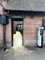 A hotel reception area with a brick facade, a sign above the entrance, and a parking meter to the right.