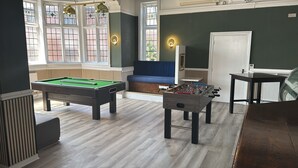 Una habitación con mesa de billar, mesa de futbolín y un sofá.