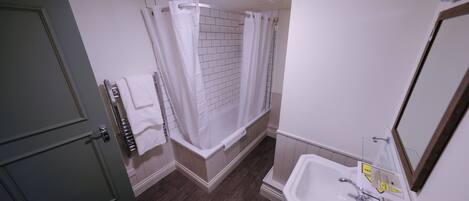 A bathroom with a shower, a sink, and a door.