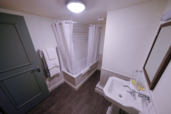 Un baño con ducha, lavamanos y puerta.