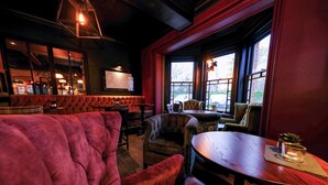 A cozy interior with plush seating, a wooden table, and large windows offering a view.