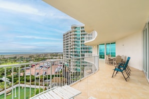 A balcony with a view of a parking lot and a building with a unique curved design. - Caribe Resort by Hosteeva (Orange Beach)