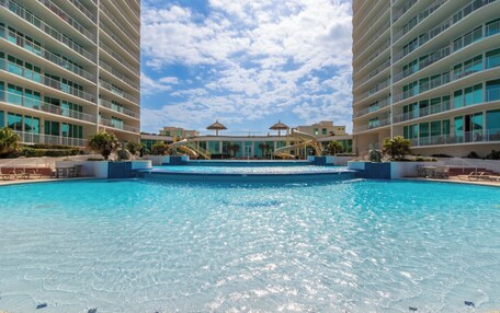 A large swimming pool surrounded by modern buildings with multiple balconies.