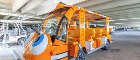 Un vehículo compacto y naranja, de diseño singular, estacionado bajo una estructura de hormigón.