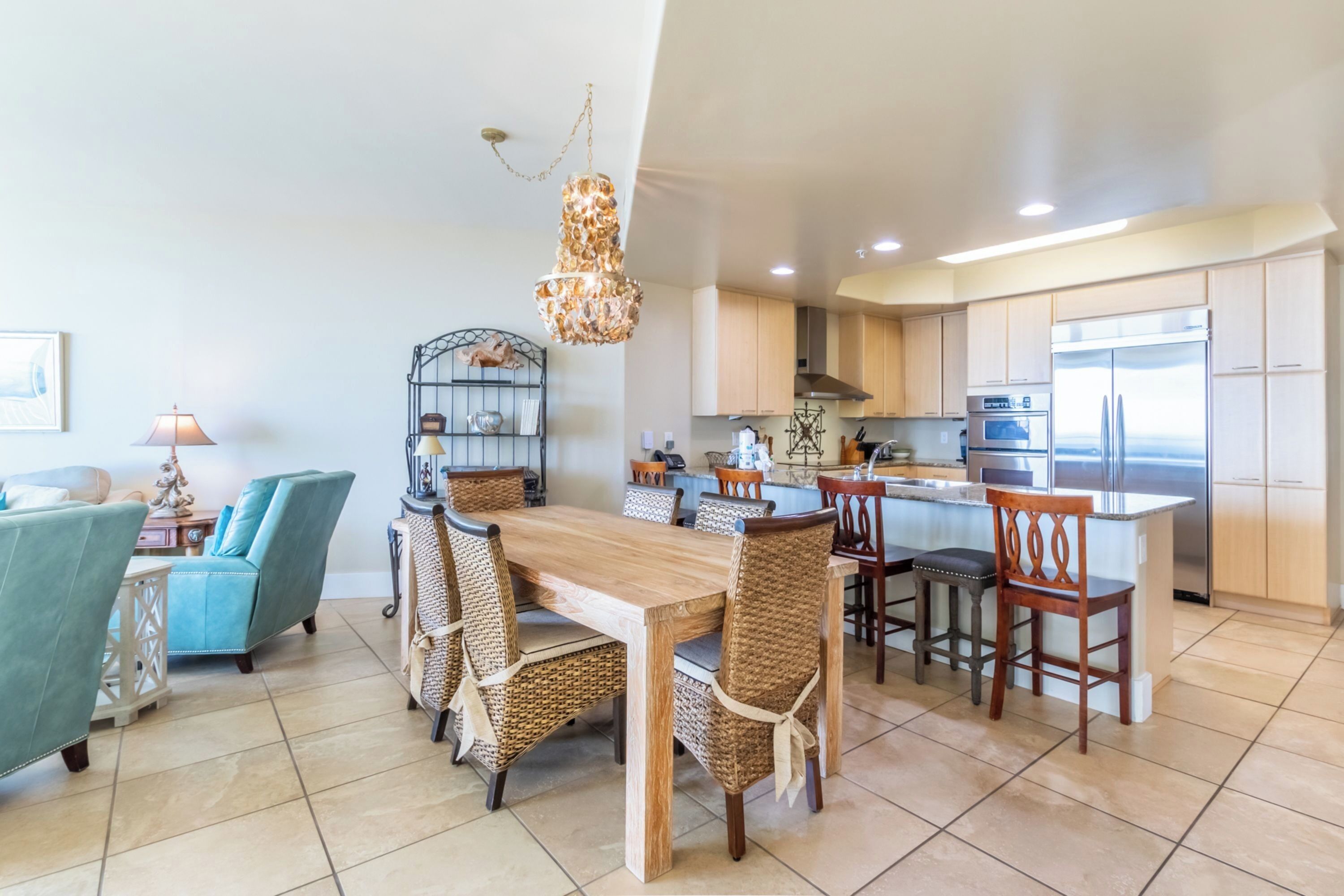 A spacious kitchen with modern appliances, a dining area with wicker chairs, and a large island.