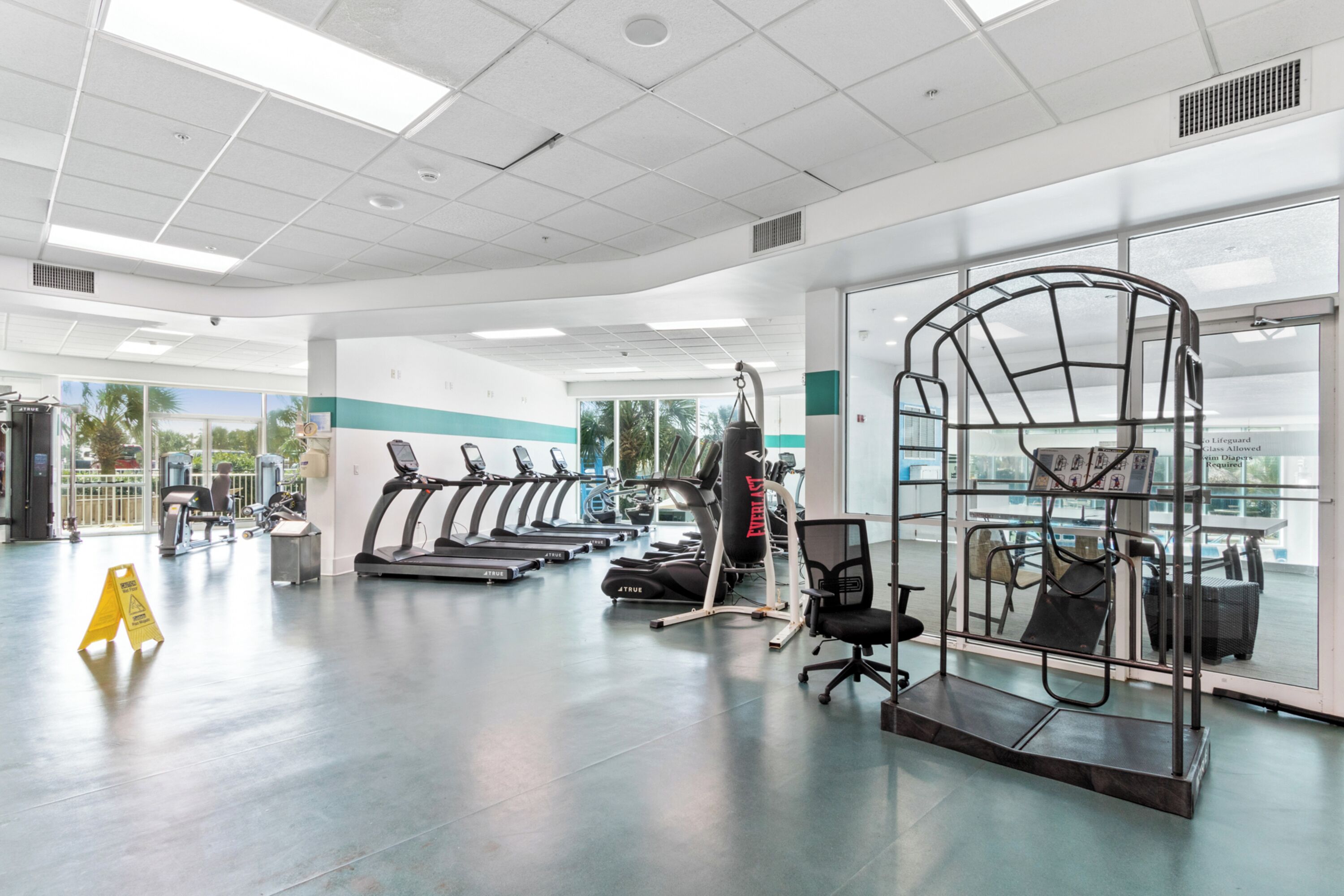 Un gimnasio con cintas de correr, bicicletas estáticas y un saco de boxeo.