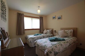 Ein Schlafzimmer mit zwei Betten, einem Schreibtisch und einem Fenster mit Vorhängen.