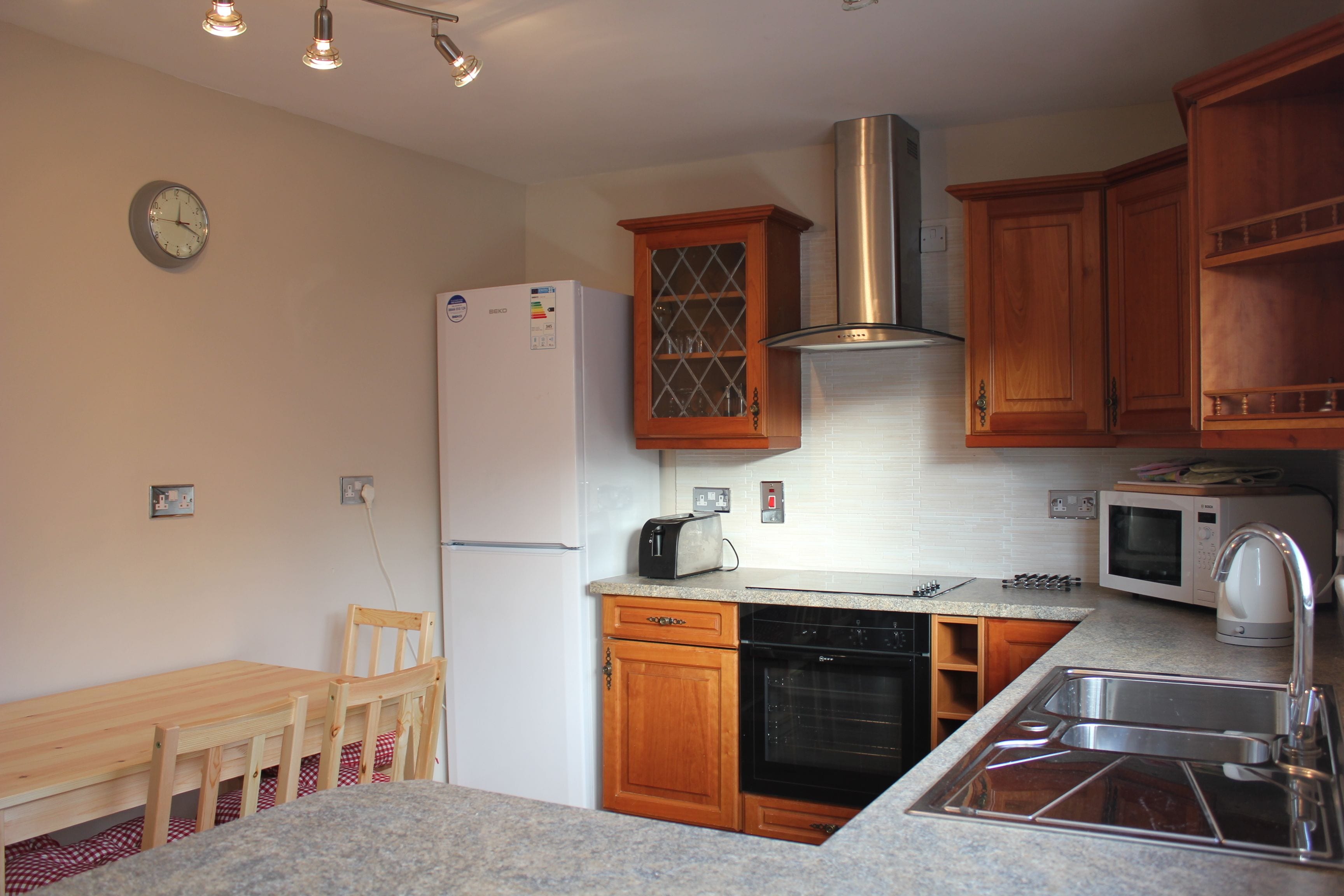 A compact kitchen with wooden cabinets, a built-in oven, a microwave, and a sink.