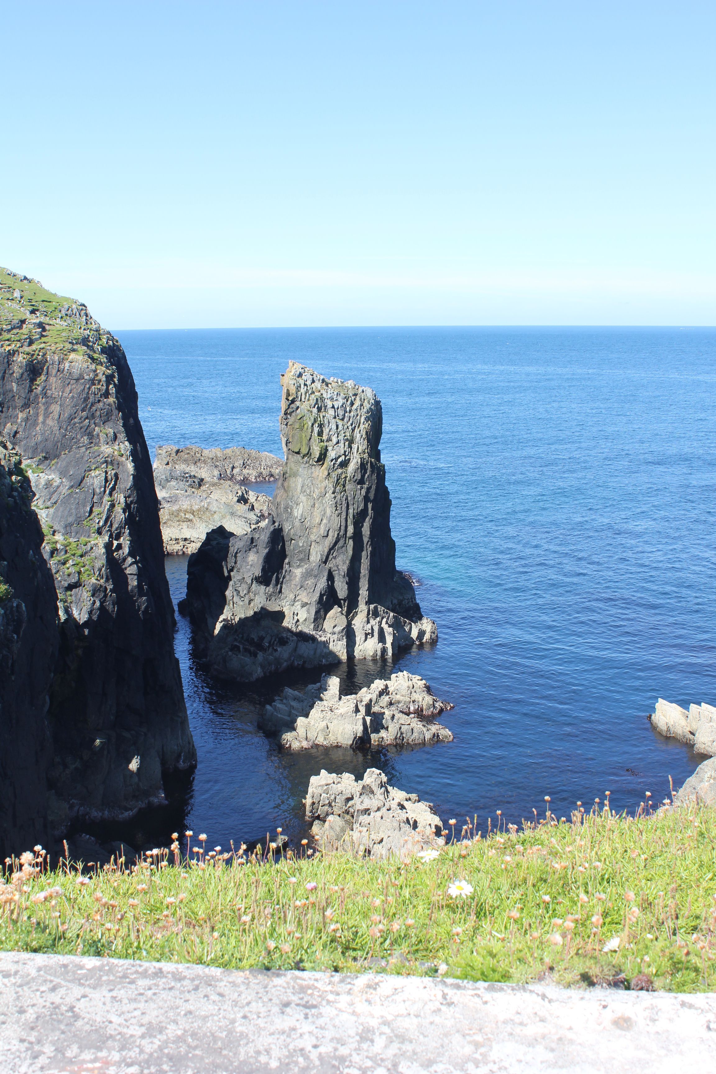 Paisaje costero con acantilados rocosos y un mar azul cristalino.