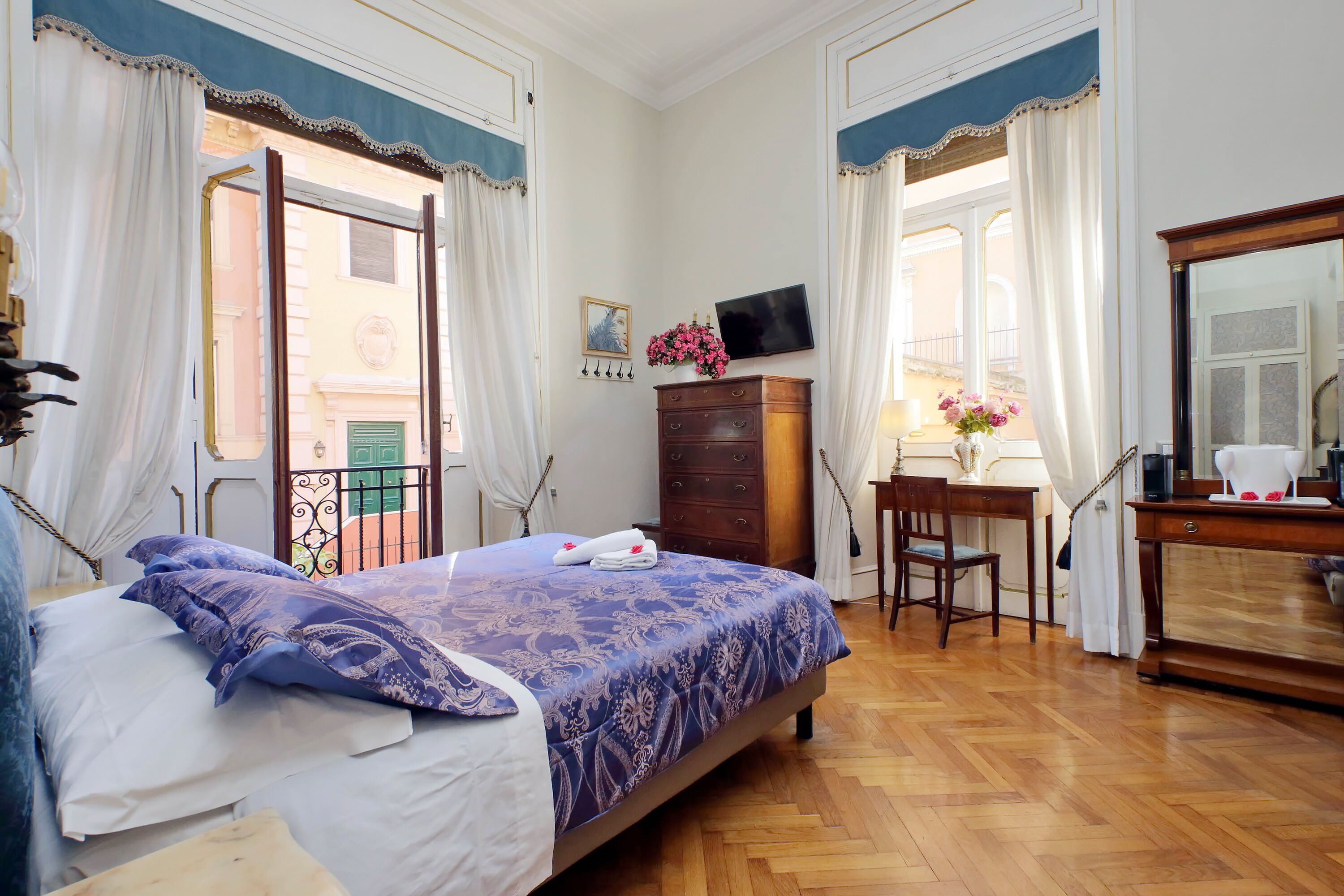 Quarto de hotel com cama, penteadeira de madeira, escrivaninha e espelho.