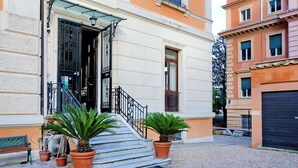 A building with a staircase leading to a door, potted plants, and a bench. - Domus Monamì Luxury Suites (Rome)