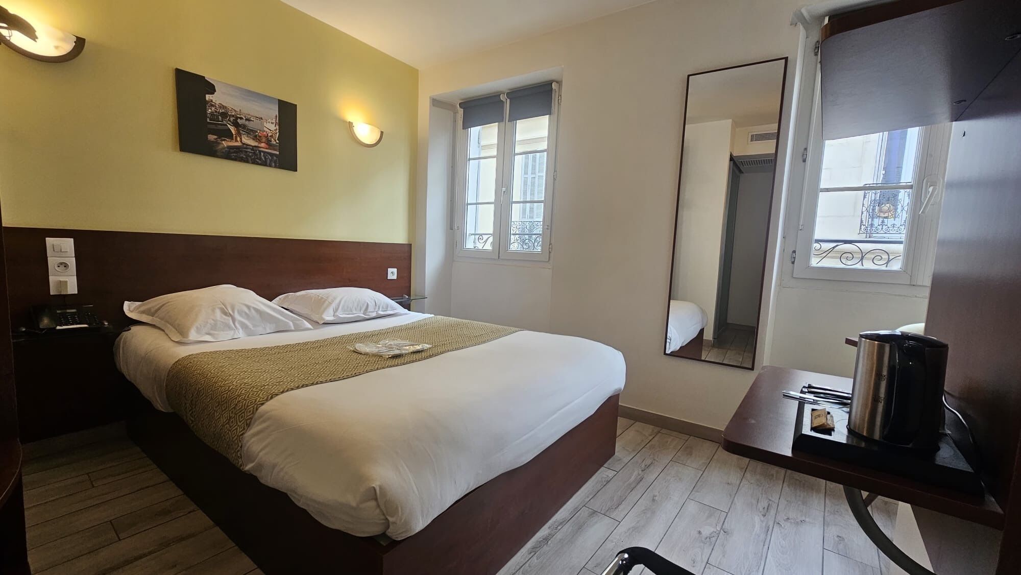 Habitación de hotel con cama, mesita de noche, lámpara y un cuadro en la pared.