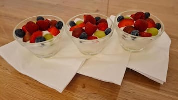 Tres ensaladas de frutas en una mesa de madera con servilletas blancas.