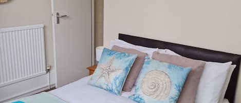 Een hotelkamer met een bed, een schilderij van een strandhuis en een deur.