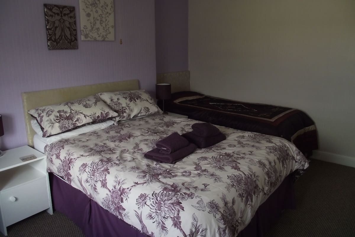A double bed with floral bedding, a nightstand, and a lamp.
